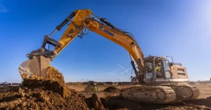 XCMG excavator digging on a real construction site under clear blue sky, showcasing power, durability, and heavy-duty performance.